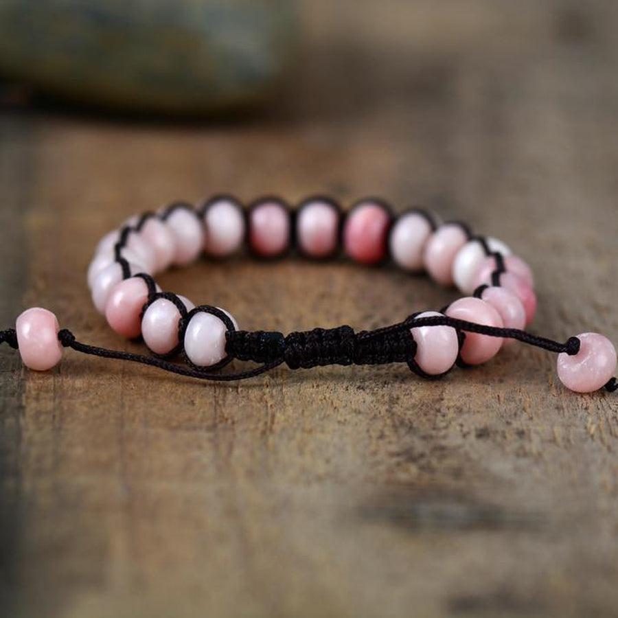 Gros plan sur perles d'opale rose, cordon tissé noir