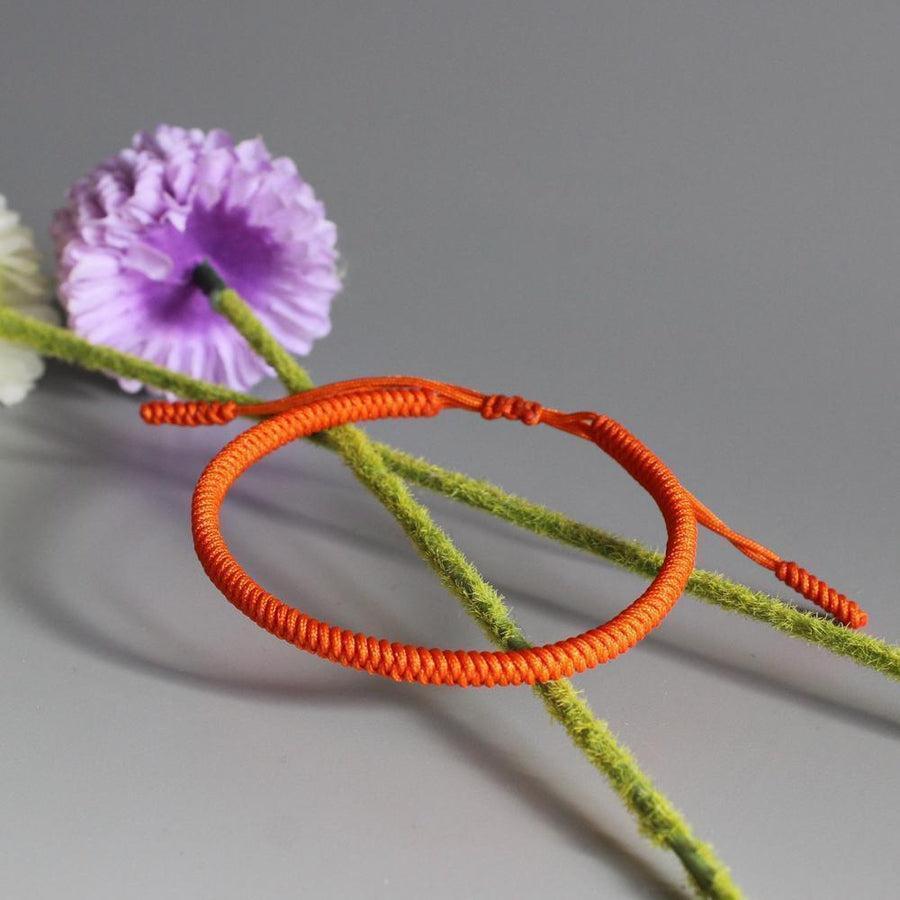 Bracelet bouddhiste orange en corde tressée sur fond blanc