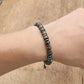 Bracelet en Bronzite et Hématite posé sur une surface en bois