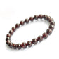 Gros plan sur les perles rouges du bracelet grenat
