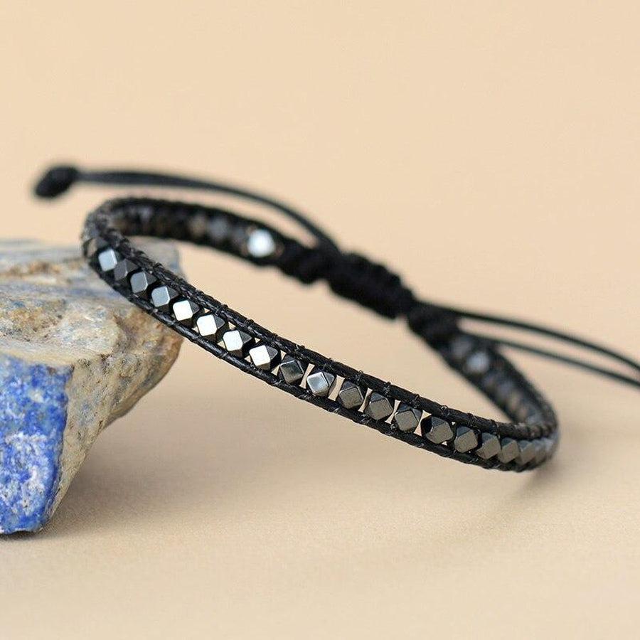 Bracelet en hématite facettée sur fond blanc, cordon noir