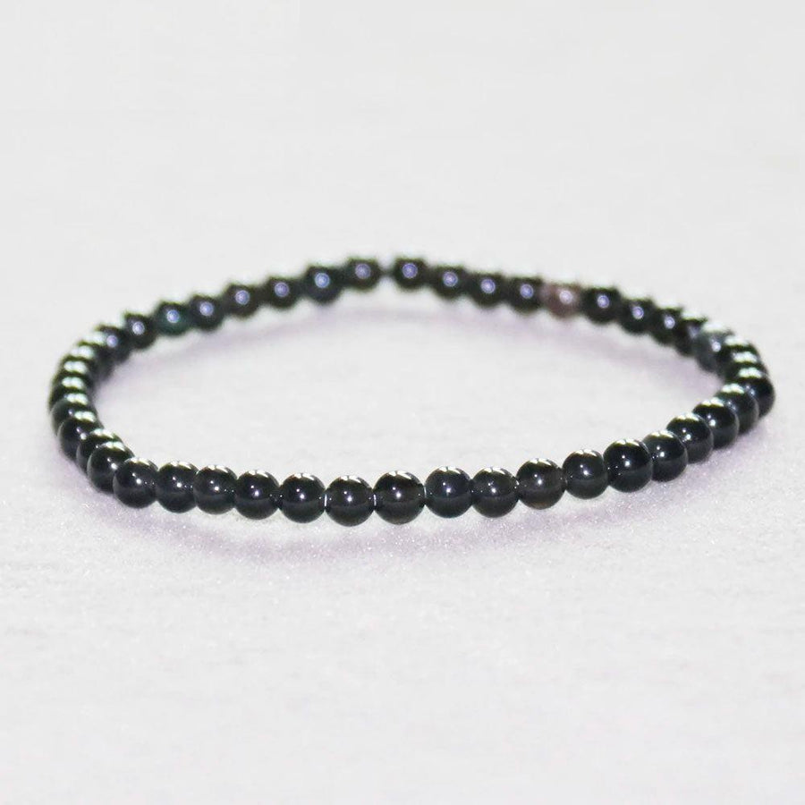 Bracelet en tourmaline noire posé sur une surface en bois