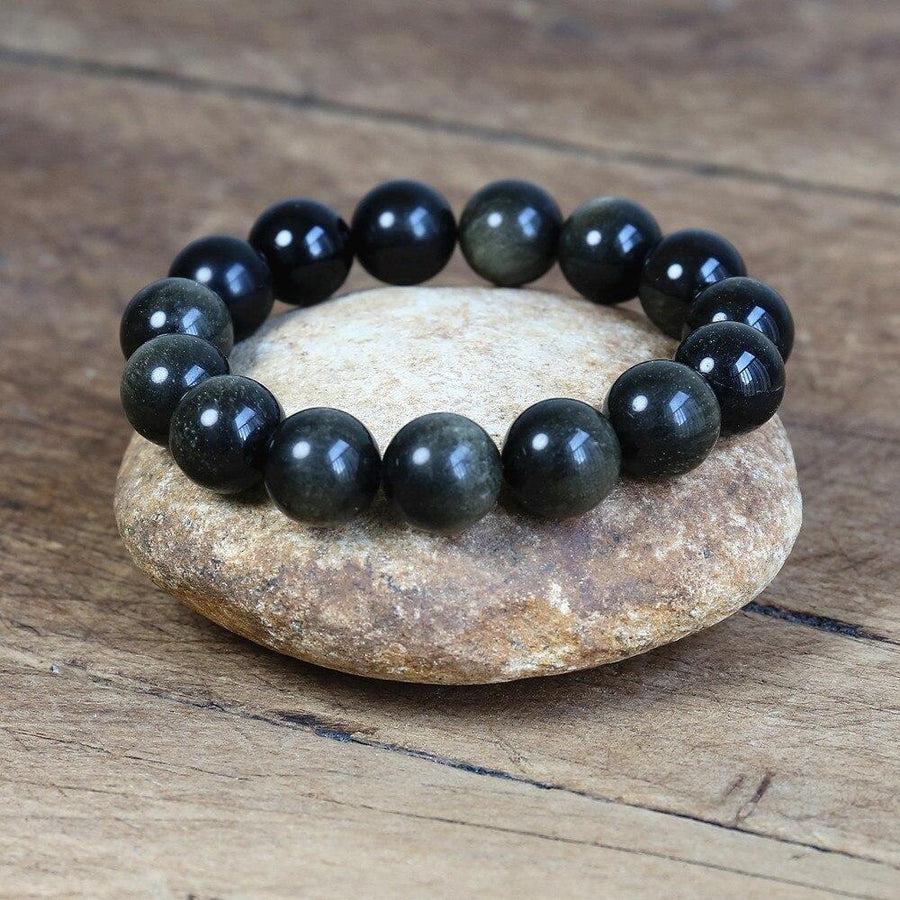 Bracelet en obsidienne noire dorée posé sur une surface claire