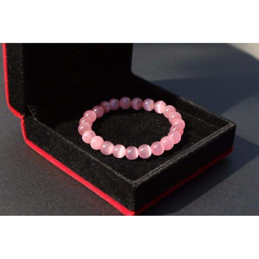 Bracelet en opale rose posé sur une surface en bois
