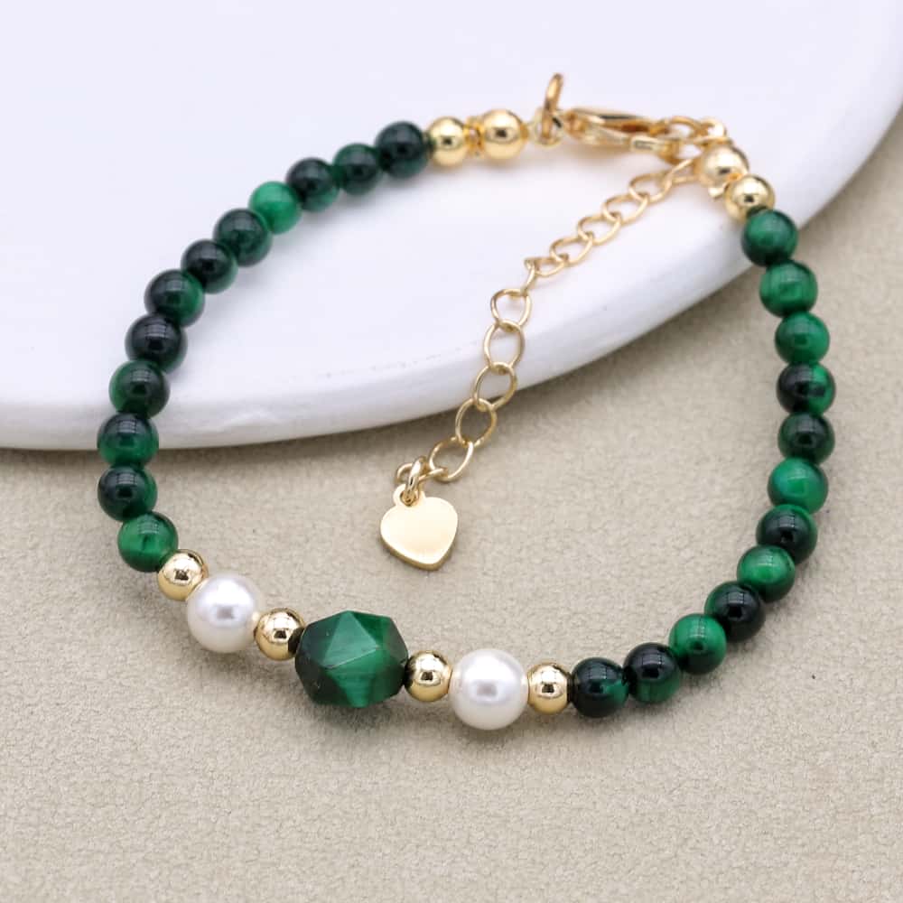 Bracelet avec perles émeraude et nacre sur fond blanc