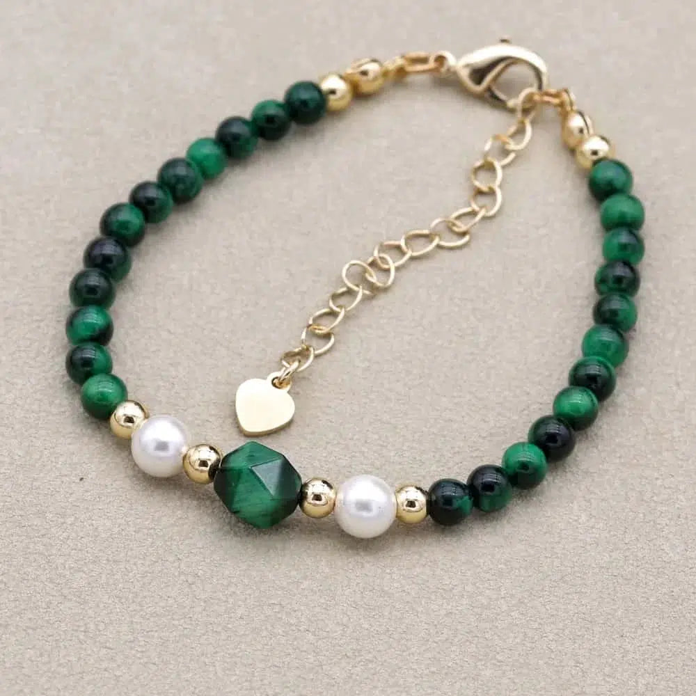 Bracelet émeraude et nacre posé sur une surface en bois