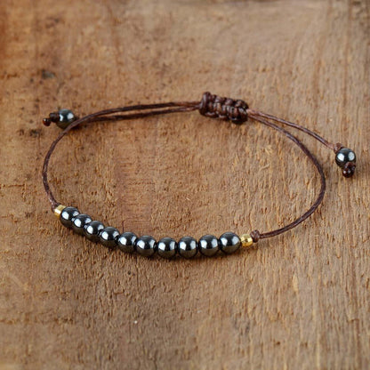 Bracelet en hématite posé sur une surface en bois clair
