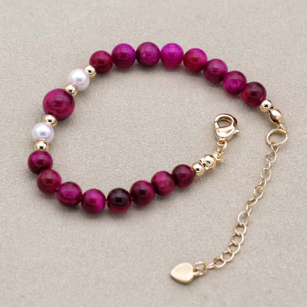 Gros plan sur les perles dorées et roses du bracelet