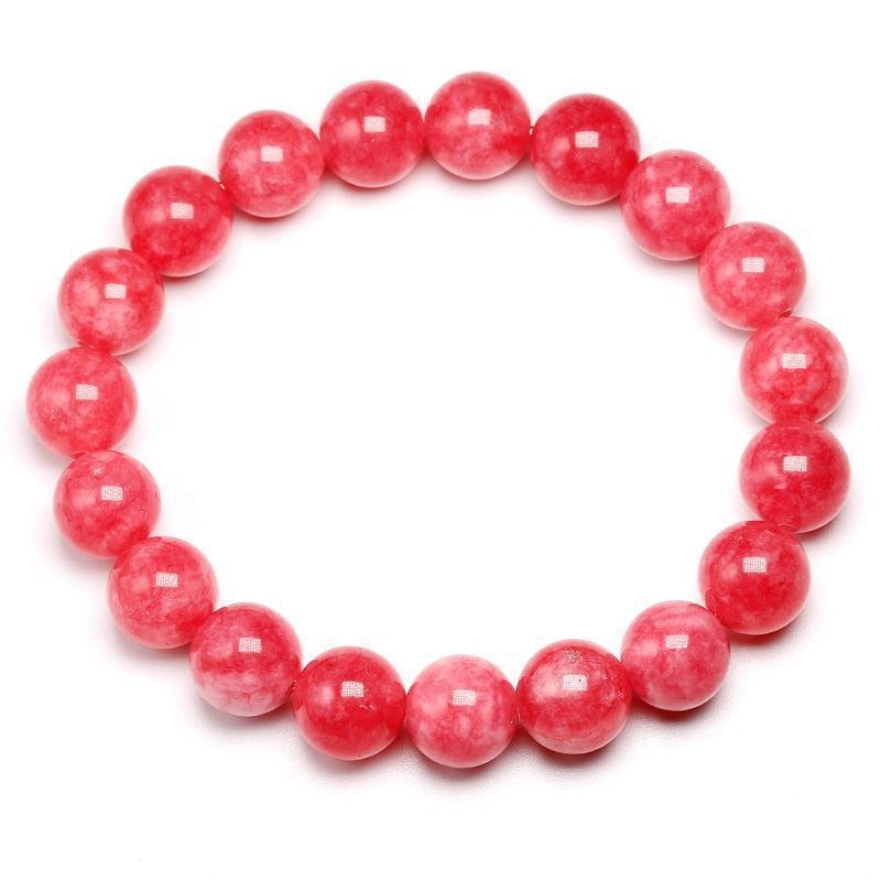Bracelet en rhodonite posé sur une surface en bois clair