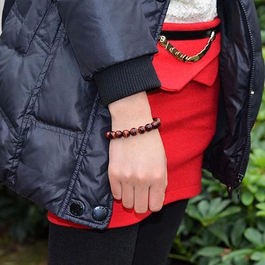 Bracelet Œil de tigre rouge posé sur une surface claire
