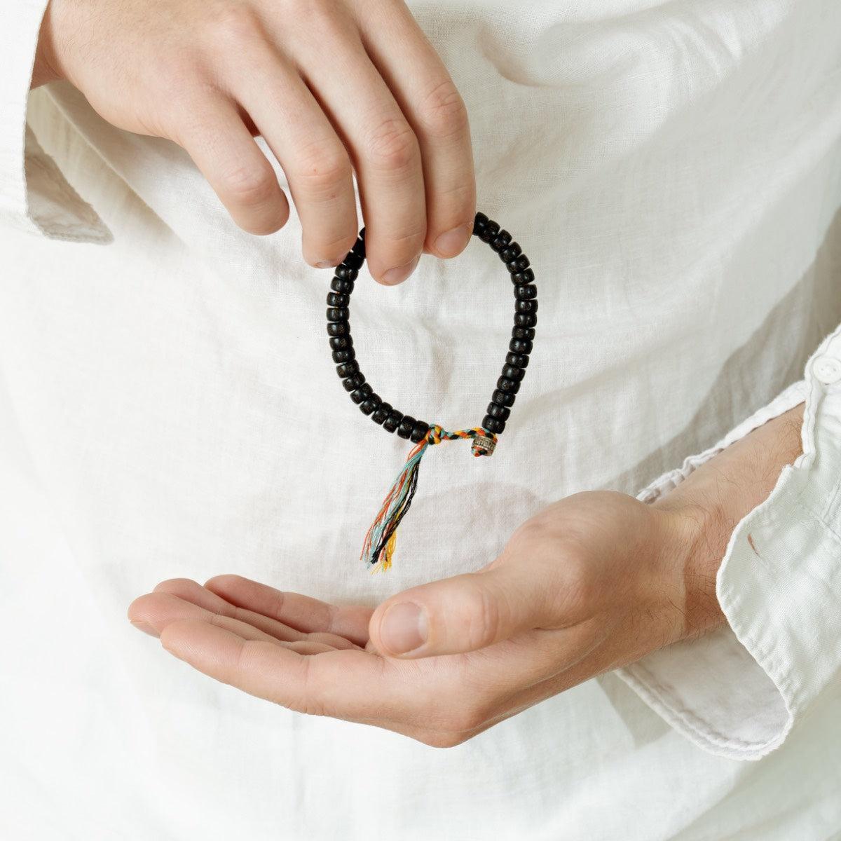 Détail des perles gravées sur un bracelet bouddhiste coloré