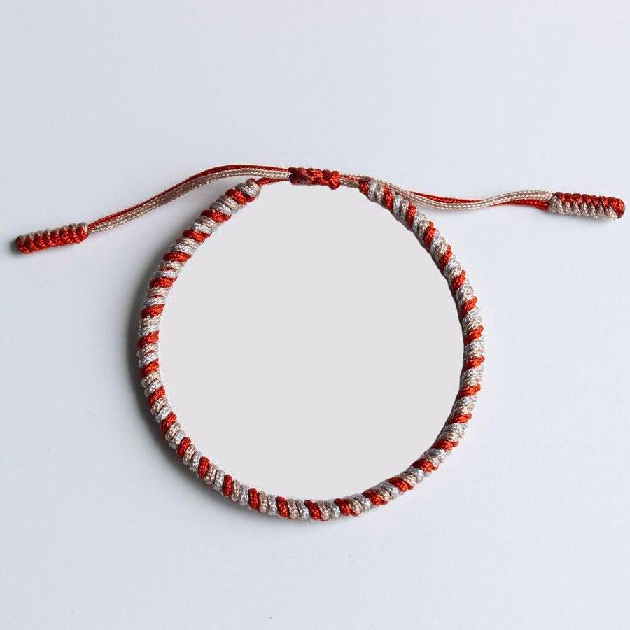 Bracelet tibétain bicolore avec nœuds traditionnels sur fond blanc