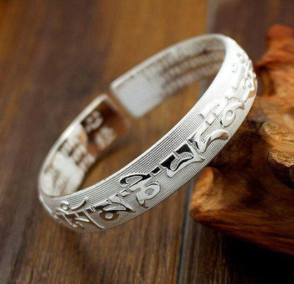 Détail des inscriptions du mantra sur le bracelet argenté