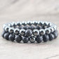 Deux bracelets en hématite et pierre de lave sur fond neutre