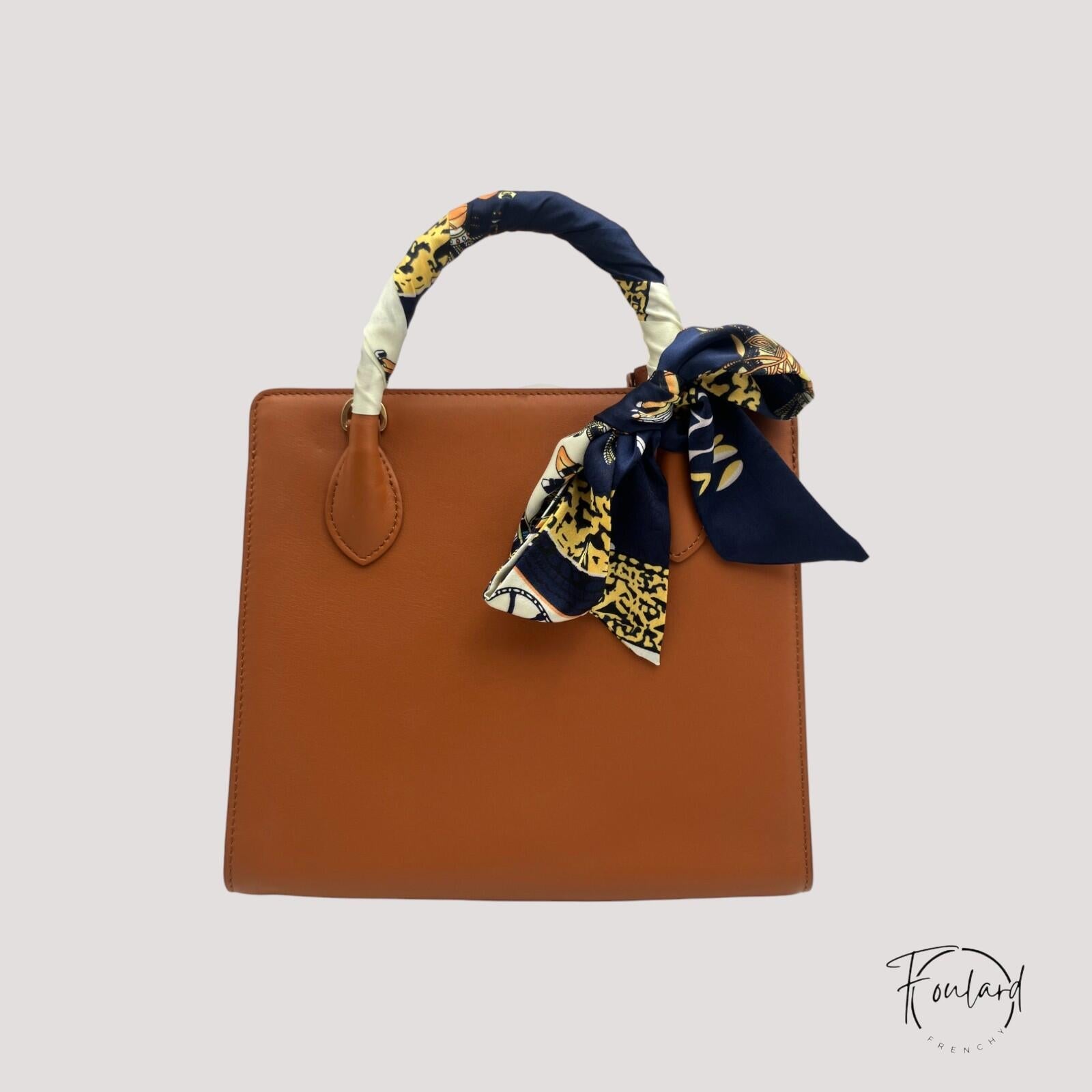 Gros plan sur motifs équestres dorés et ivoire du foulard