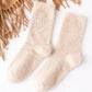 Chaussettes crème posées sur un lit blanc
