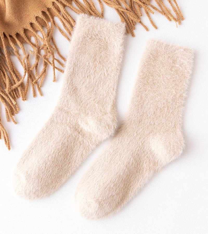 Chaussettes crème posées sur un lit blanc