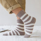 Chaussettes montantes grises avec rayures blanches, posées à plat