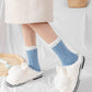 Chaussettes en laine synthétique bleue posées sur une surface claire