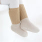 Chaussettes polaires pour bébé en camel, pliées sur une surface
