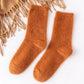 Chaussettes sherpa orange posées sur une surface blanche