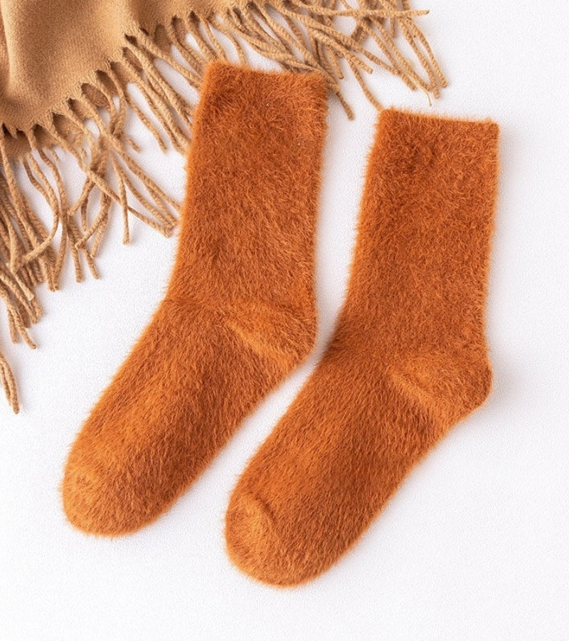 Chaussettes sherpa orange posées sur une surface blanche