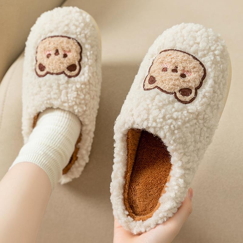 Gros plan sur le motif ourson brodé des chaussons en peluche