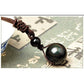 Gros plan sur le pendentif obsidienne, reflets verts et bleus