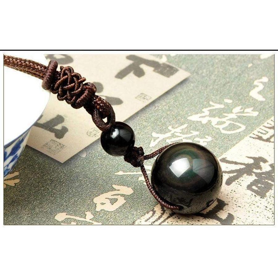 Gros plan sur le pendentif obsidienne, reflets verts et bleus