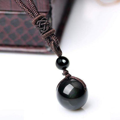 Collier obsidienne sur fond noir, mettant en valeur les reflets