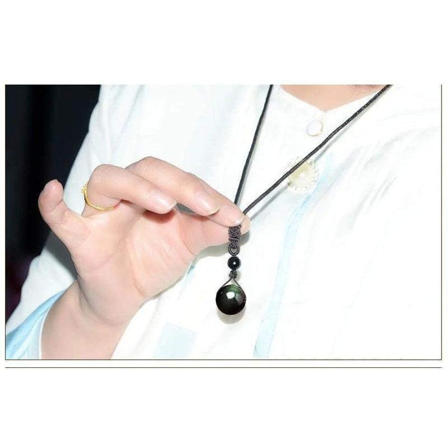 Collier obsidienne posé sur une surface en bois clair