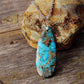 Gros plan sur le pendentif turquoise et chaîne dorée