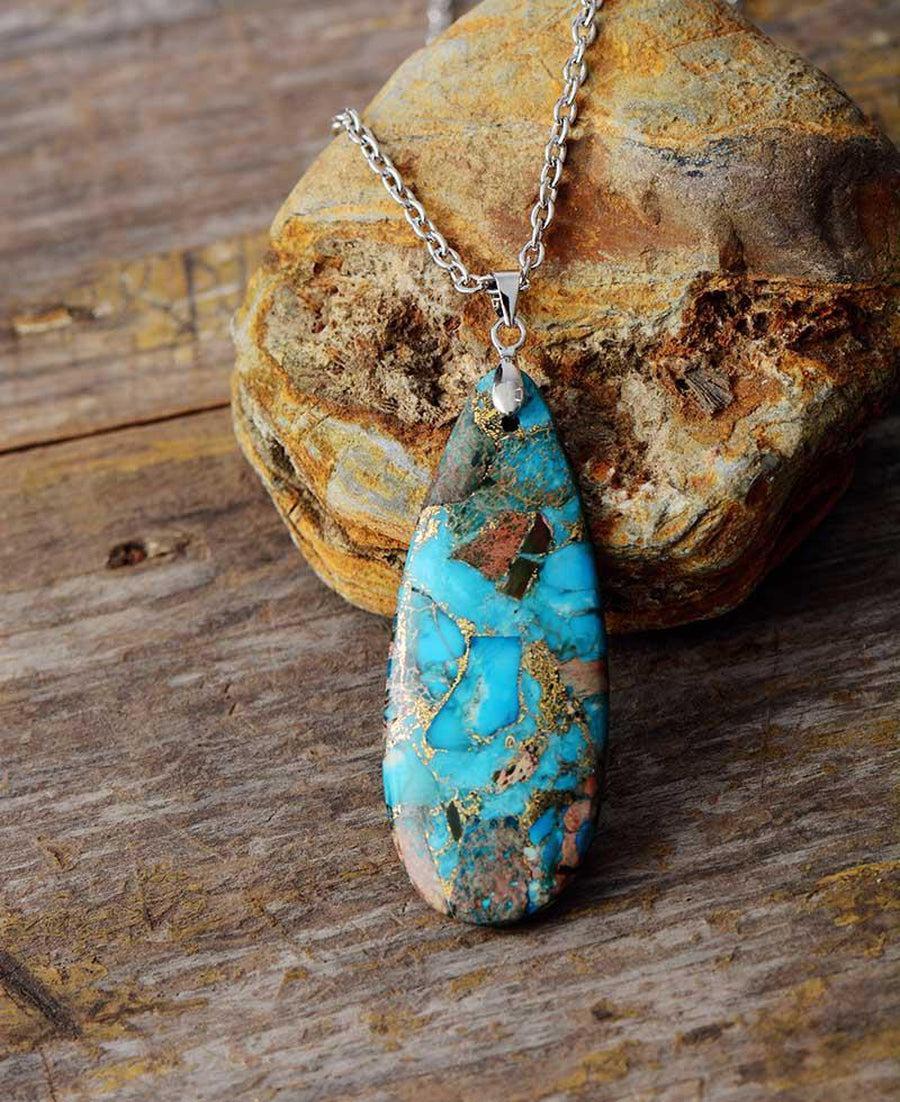 Gros plan sur le pendentif turquoise et chaîne dorée