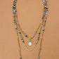 Collier sautoir bohème en trois rangs sur fond neutre