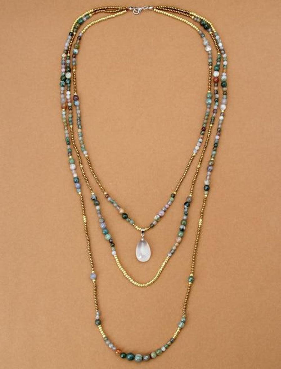 Collier sautoir bohème en trois rangs sur fond neutre