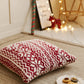 Coussin rouge avec motifs flocons blancs sur canapé neutre