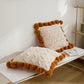 Coussin crème avec pompons caramel en matière moumoute