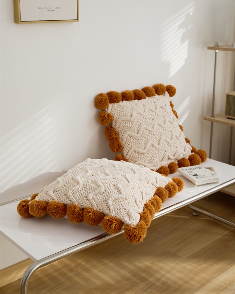 Coussin crème avec pompons caramel en matière moumoute