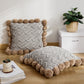 Coussin gris avec pompons marron sur canapé beige