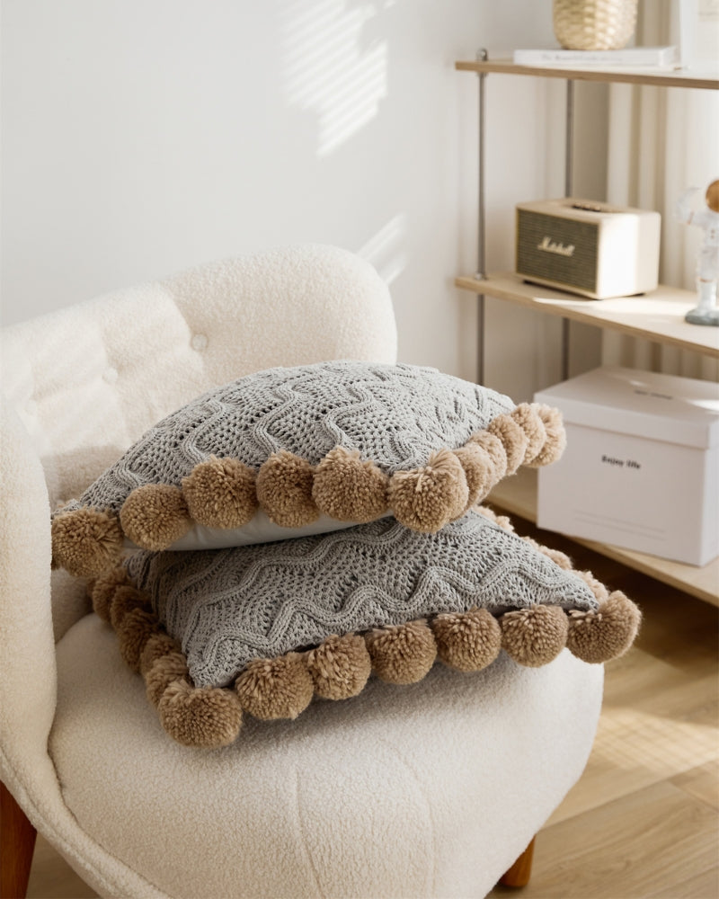 Gros plan sur pompons marron du coussin gris