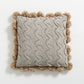 Détail des pompons marron sur le bord du coussin