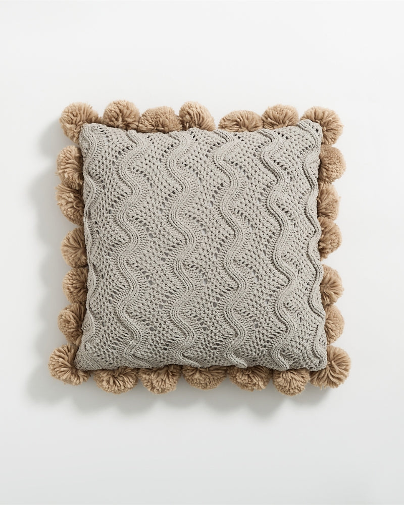 Détail des pompons marron sur le bord du coussin