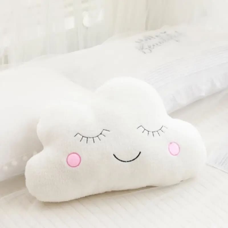 Coussin nuage moelleux pour bébé posé sur un lit rose