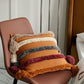Coussin orange avec motifs colorés et pompons décoratifs