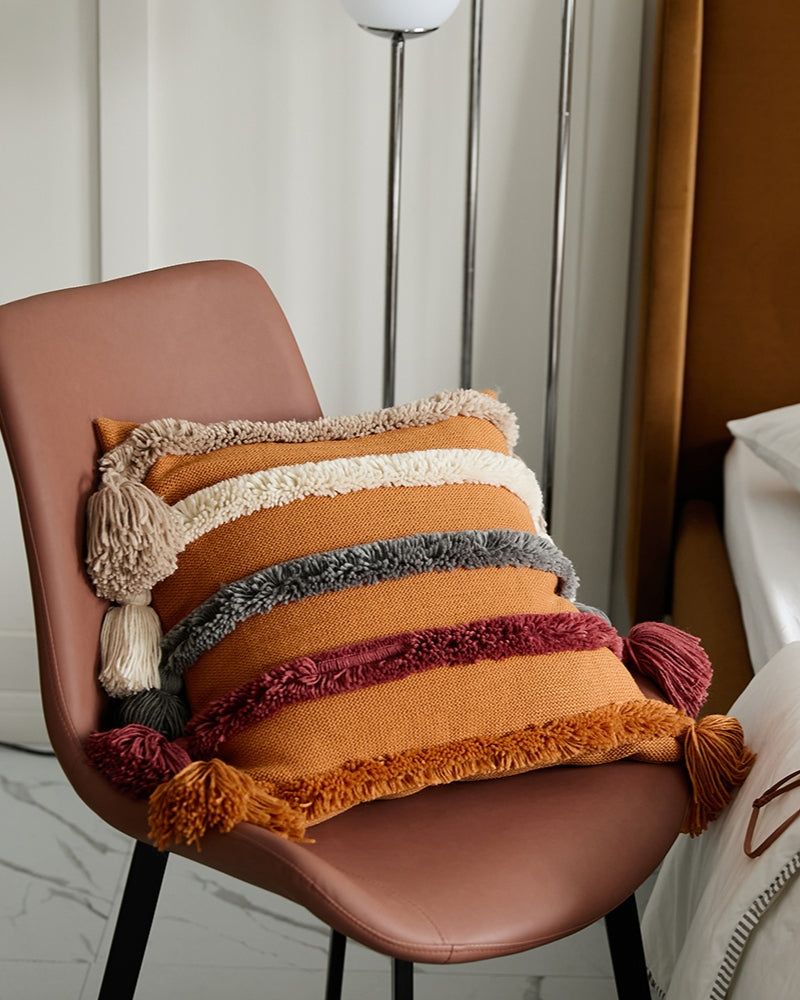 Coussin orange avec motifs colorés et pompons décoratifs