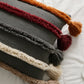 Coussin bohème gris avec pompons colorés aux extrémités
