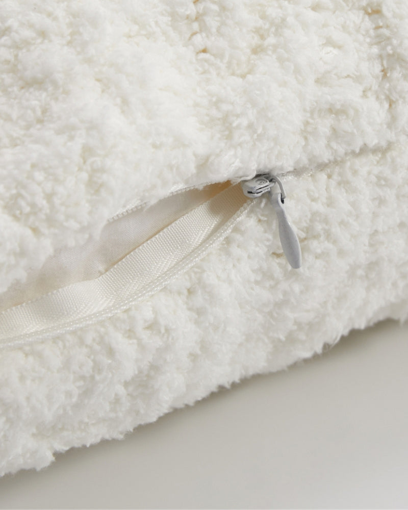 Gros plan sur les motifs croisés du coussin blanc
