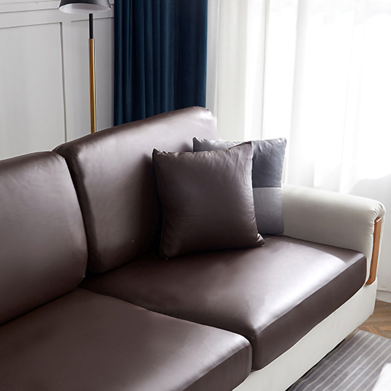 Housse de coussin en simili cuir beige sur canapé gris