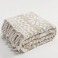 Couverture beige et blanche drapée sur un fauteuil