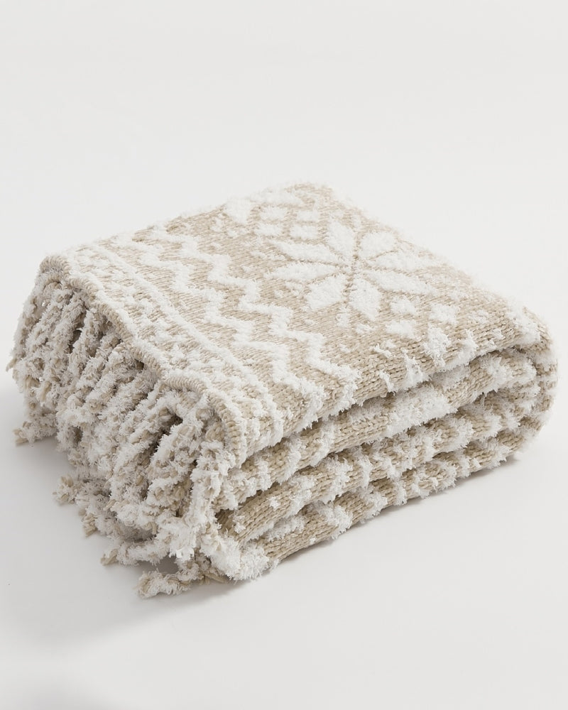 Couverture beige et blanche drapée sur un fauteuil